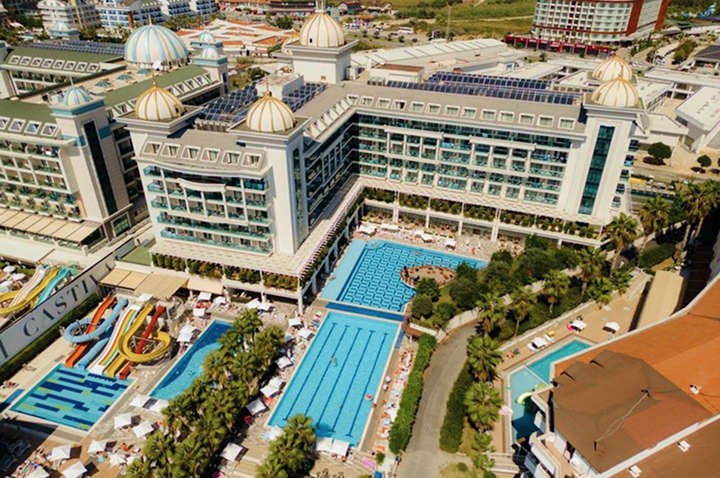 Luftaufnahme des Hotels mit dem Poolbereich, umgeben von grünen Gärten und Sonnenliegen.