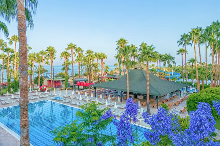 Blick auf den Pool des Strandclub-Hotels in der Türkei, umgeben von Sonnenliegen und tropischen Pflanzen.