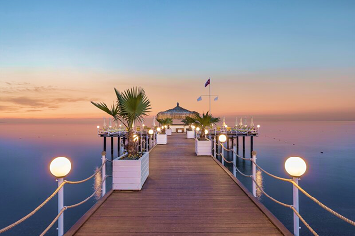 Ein romantischer Pier mit Lichtern, der in den sanften Farben des Sonnenuntergangs erstrahlt.