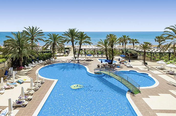 Luxuriöses Hotel mit Poolbereich am Strand, umgeben von Palmen und direktem Zugang zum Meer.