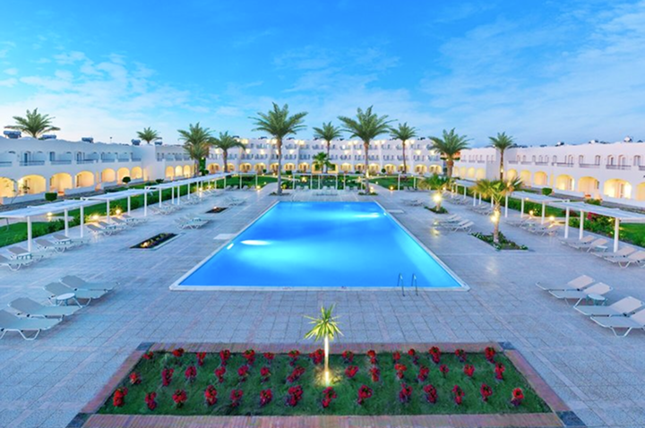 Der Hotelpool ist von üppigen Palmen umgeben, die eine entspannende Urlaubsatmosphäre schaffen.