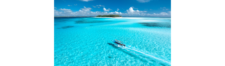 Ein Boot segelt durch das klare, blaue Wasser um eine Insel herum.