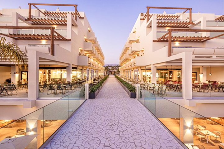 Ein schöner Weg führt zu einem Hotel, das über eine Terrasse mit Sitzgelegenheiten im Freien verfügt.