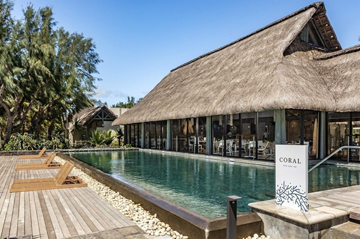 Der Pool im Resort ist von traditionellen Strohdächern umgeben, die eine entspannte Urlaubsatmosphäre schaffen.