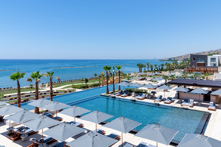 Hotelpool mit Liegen und Sonnenschirmen vor Meer und Küstenlandschaft. Hotelpool mit Liegen und Sonnenschirmen vor Meer und Küstenlandschaft.