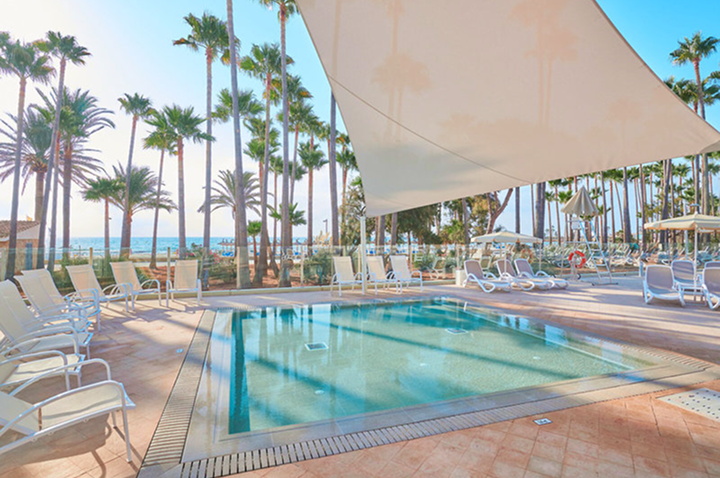 Ein Pool mit Liegen und Palmen im Hintergrund, ideal für Entspannung und Urlaubsspaß.