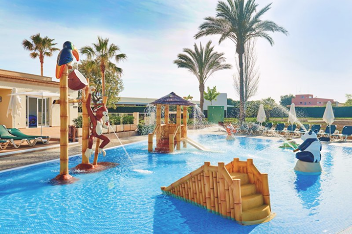 Entspannender Poolbereich mit Liegen und Schirmen vor einem Hotel, perfekt für einen sonnigen Tag am Wasser.