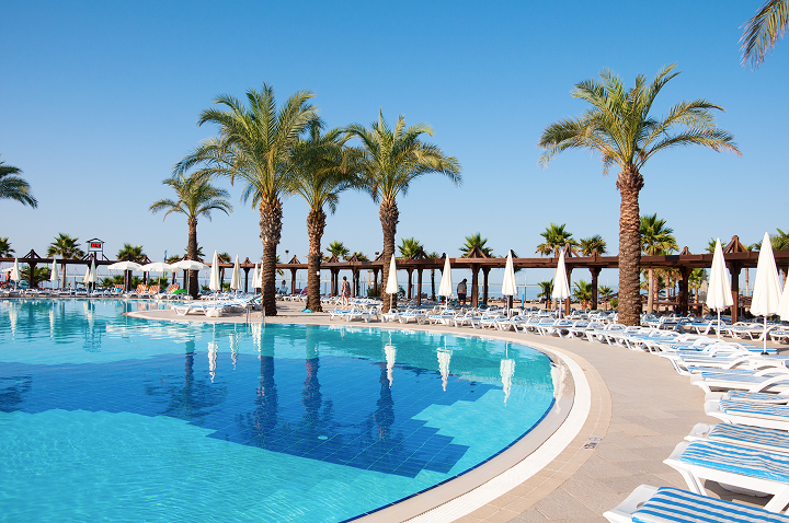 Ein weitläufiger Pool, umgeben von Liegen und Sonnenschirmen, lädt zum Entspannen und Erfrischen ein.
