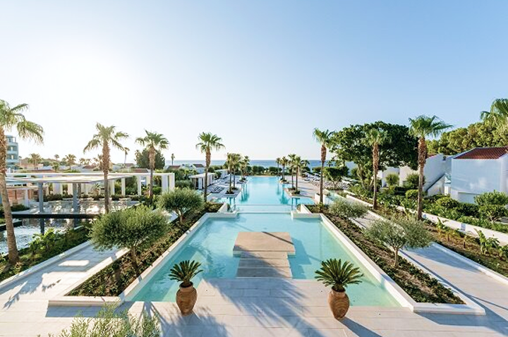 Blick auf den Pool im Strandclub des Luxushotels, umgeben von Palmen und Sonnenliegen, ideal zum Entspannen.