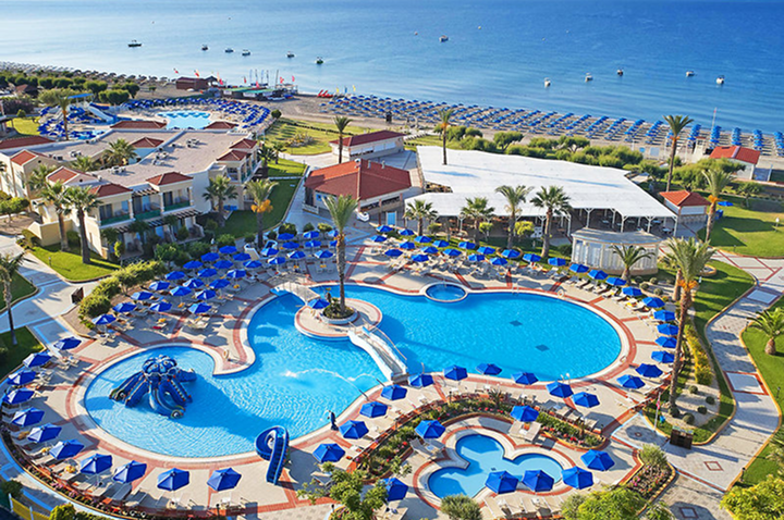 Luftaufnahme eines Resorts mit mehreren Pools, Sonnenschirmen, Gebäuden mit einer Bucht mit Sandstrand und Felsen. Luftaufnahme eines Resorts mit mehreren Pools, Sonnenschirmen, Gebäuden mit einer Bucht mit Sandstrand und Felsen.