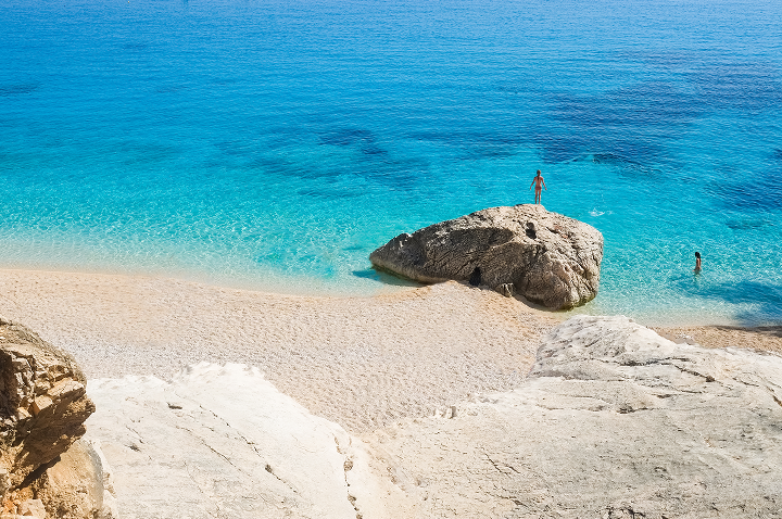 Ein malerischer Strand mit klarem Wasser und glatten Felsen, ideal für einen entspannten Tag.