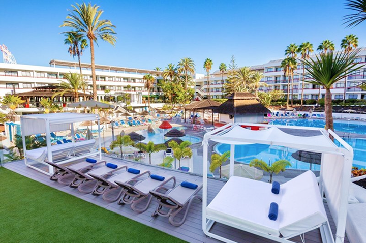 Blick auf ein Hotel mit einem erfrischenden Pool und gemütlichen Liegen für entspannte Stunden im Freien.